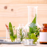 Alternative health care fresh herbal in laboratory glassware  with  stethoscope on wooden background.